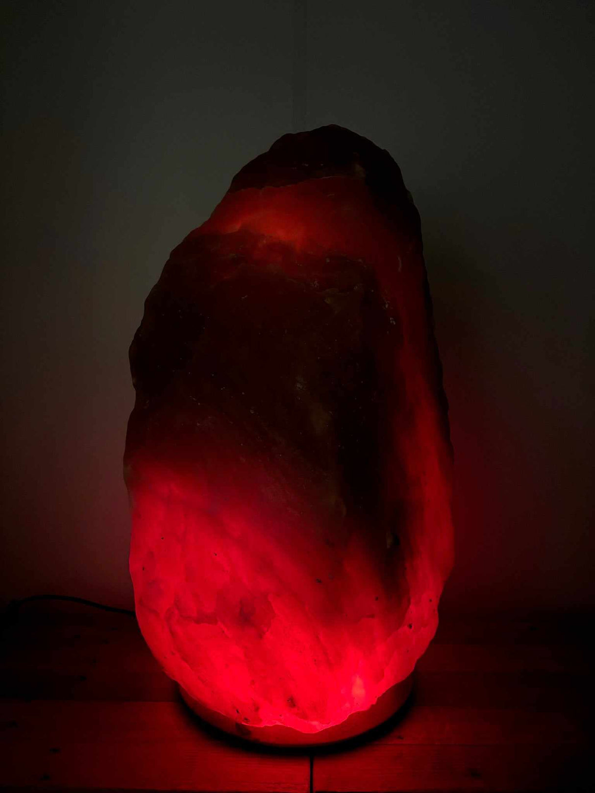 grote Himalaya zoutlamp rood met warme gloed en houten voet