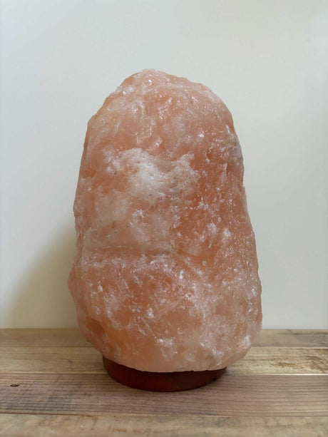 Roze Himalaya zoutlampen met warme gloed en houten voet in verschillende gewichten