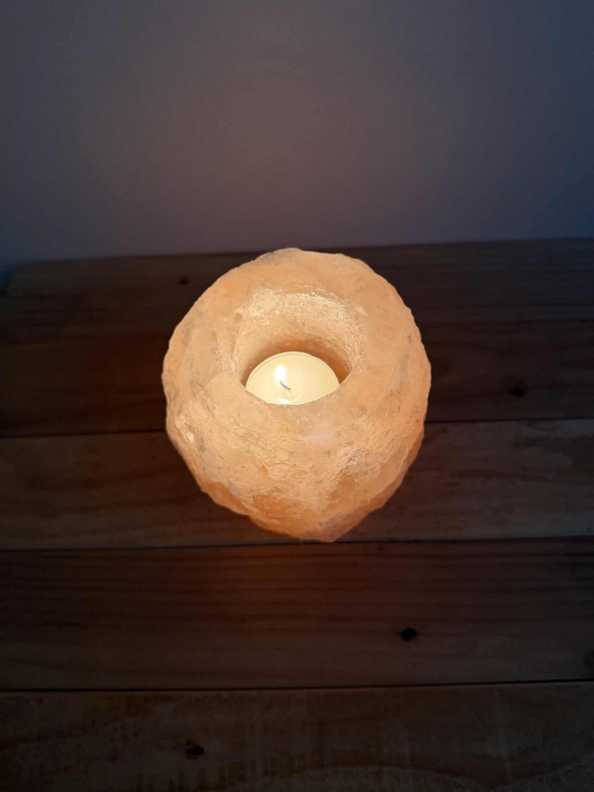 Handgemaakte roze natuurlijke zoutsteen waxinelichthouder met siliconen voetjes en zachte gloed.