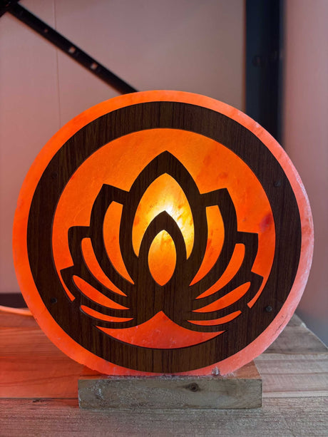 Handgemaakte Himalaya zoutlamp met 3D bloemmotief en warme oranje gloed op houten voet