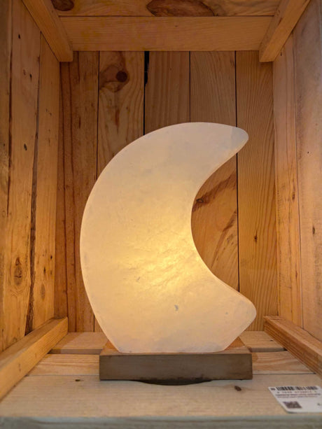 Himalaya zoutlamp in maanvorm in roze, grijs en wit met zachte, rustgevende gloed en houten voet.