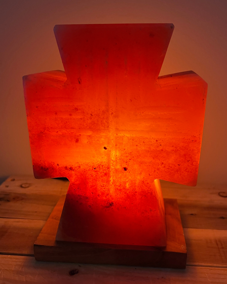 Himalaya zoutlamp in kruisvorm op houten voet, zuivert lucht en straalt warm licht met spirituele betekenis uit