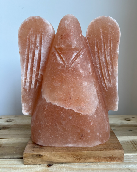 Engelvormige Himalaya zoutlamp op houten voet, straalt warm licht en brengt rust, zuivering en spirituele sfeer