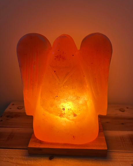 Engelvormige Himalaya zoutlamp op houten voet, straalt warm licht en brengt rust, zuivering en spirituele sfeer