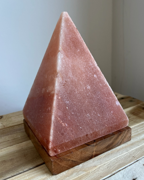 Handgemaakte piramide zoutlamp op houten voet, zuivert lucht en straalt warm, rustgevend licht voor een sfeervol interieur