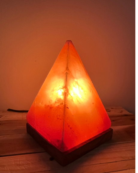 Handgemaakte piramide zoutlamp op houten voet, zuivert lucht en straalt warm, rustgevend licht voor een sfeervol interieur