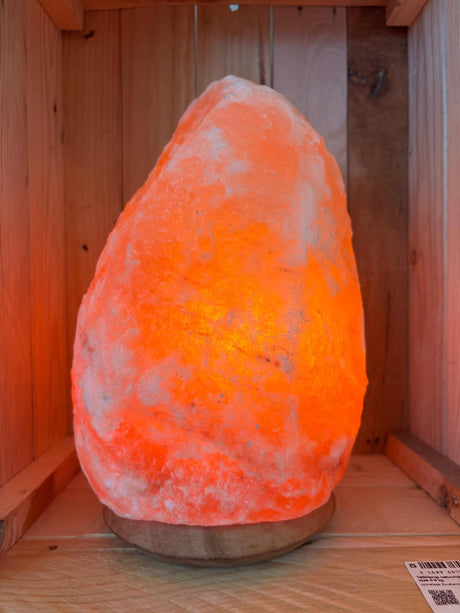 Himalaya zoutlamp van 6–8 kg met houten voet en warme amberkleurige gloed, handgemaakt van puur roze zout uit Pakistan