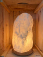 Brandende witte Himalaya zoutlamp 8-10 kg met natuurlijke structuur op houten voet