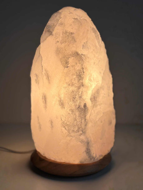 Witte Himalaya zoutlamp van 10-12 kg met houten voet, inclusief kabel en lampje, geschikt voor sfeervolle verlichting in huis.